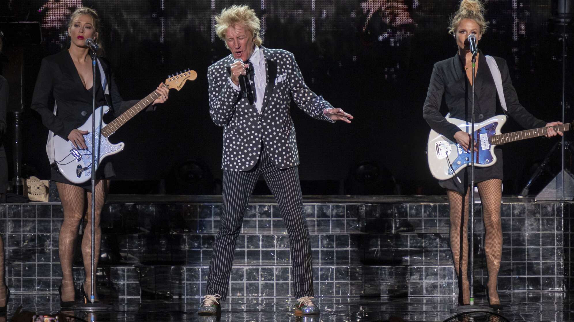 Rod Stewart auf der Bühne zwischen zwei Gitarristinnen